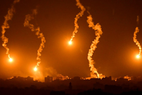 Flares dropped by Israeli forces illuminate the night sky above the Gaza Strip