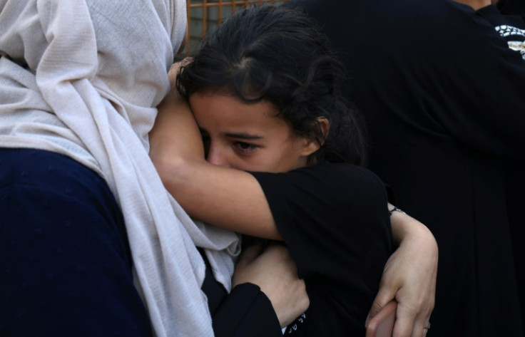 A Palestinian woman comforts a little girl as they collect the body of a relative for burial from the al-Nasser hospital in Khan Yunis in the southern Gaza Strip on November 9, 2023