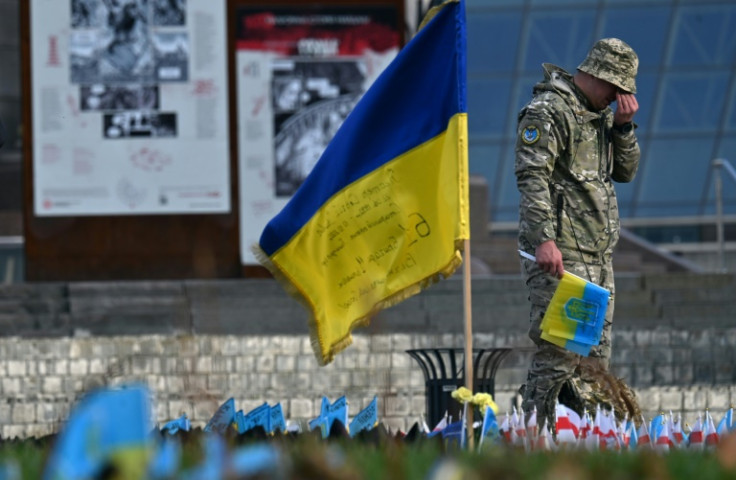 A serviceman mourns next to a Ukrainian flag at a makeshift memorial for fallen soldiers in Kyiv