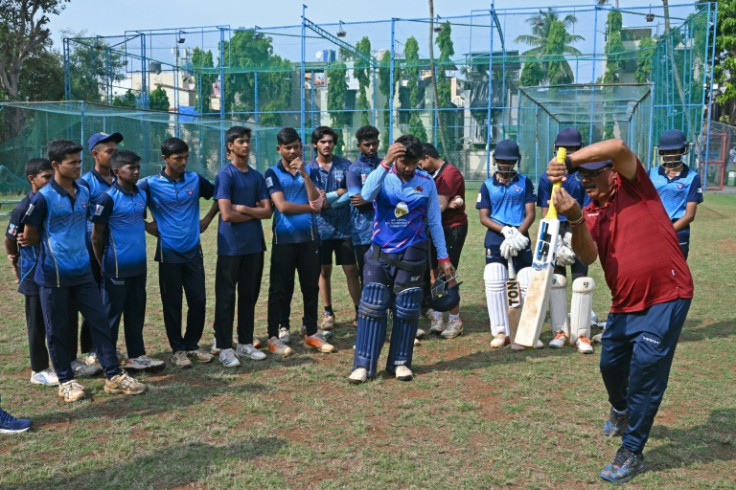 India's captain Rohit Sharma's boyhood cricket coach Dinesh Lad (R) gives training tips to young cricketers during a practice session at the Swami Vivekanand International School in Mumbai