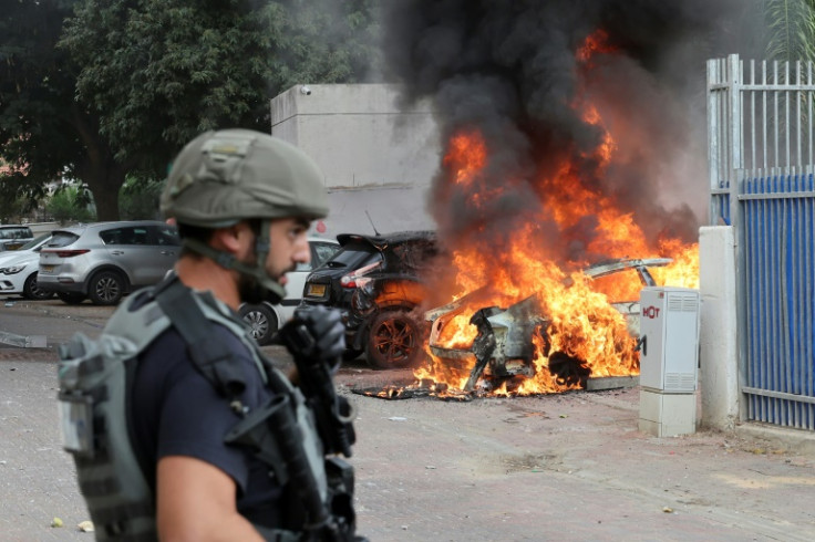 A member of the Israeli security forces near a car hit by a rocket fired from Gaza, in the southern Israeli city of Sderot, on October 9, 2023