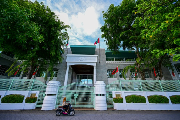A woman rides past the president's office in Male, the capital of the Maldives
