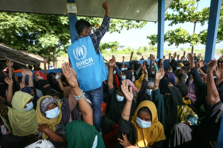 A UNHCR worker talks to Rohingya refugees who landed in western Indonesia on Sunday
