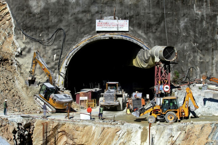 Rescue workers stand at an entrance of the under-construction road tunnel, days after it collapsed