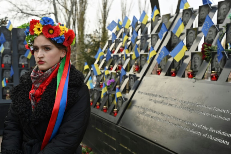A Ukrainian woman stands next to a memorial for the dozens of people killed during the Maidan protests a decade ago
