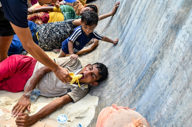 A man gives a banana to a newly-arrived Rohingya refugee resting on a beach in Sabang island, Aceh province