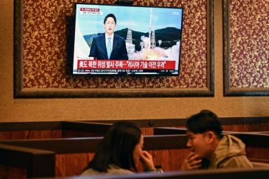 Customers sit near a television showing a news broadcast at a restaurant in Seoul on November 21, 2023, after North Korea fired what it claims is a military spy satellite
