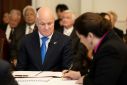 Christopher Luxon (L) looks on as Governor General Dame Cindy Kiro signs documents which formally made him Prime Minister of New Zealand on Monday