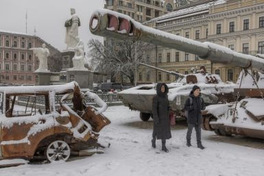 Kyiv residents walk past destroyed Russian military vehicles blanketed in snow in the centre of the Ukrainian capital