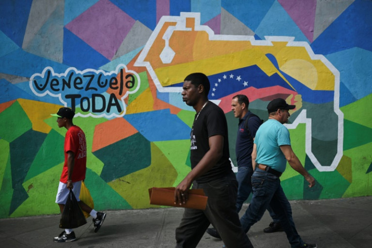 People pass a mural in Caracas campaigning for a referendum on the status of the oil-rich Essequibo region, controlled by Guyana but claimed by Venezuela