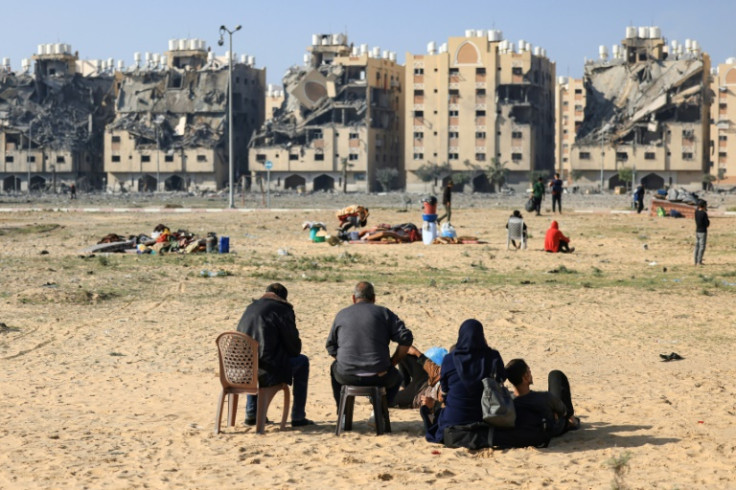 Residents of a Qatari-funded housing complex in Khan Yunis in the southern Gaza Strip sit with what belongings they could grab before it was hit by an Israeli strike