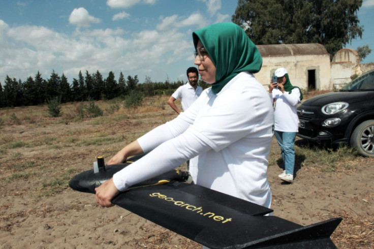 Imen Hbiri, the founder of RoboCare, prepares to fly a drone over an agricultural area to scan the trees from the air