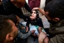 People try to comfort a woman holding the body of her baby girl in the courtyard of the Al-Najjar hospital