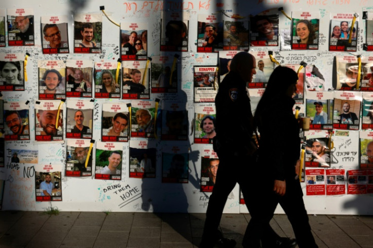 People pass by pictures of Israeli hostages held in Gaza since the October 7 attacks by Palestinian Hamas militants, posted on a wall in Tel Aviv