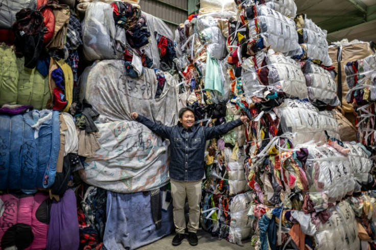 Logistics manager Osamu Ubakai stands with bundles of secondhand clothes at a warehouse in Inashiki city, Ibaraki Prefecture