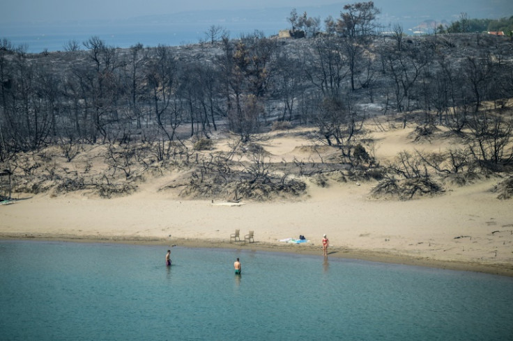-- AFP PICTURES OF THE YEAR 2023 --A woman enters the sea from a beach where wildfires destroyed the woods, at Glystra near the village of Gennadi in the southern part of the Greek island of Rhodes, on July 27, 2023