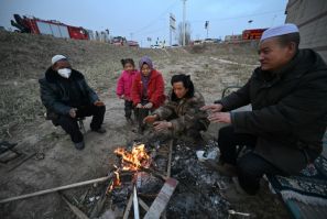 People huddle around a fire after an earthquake in northwest China’s Gansu province killed 131 people and damaged thousands of buildings
