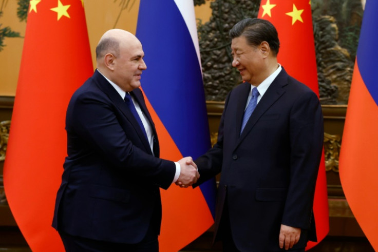 Russian Prime Minister Mikhail Mishustin (L) and Chinese President Xi Jinping shake hands before their meeting Wednesday in Beijing