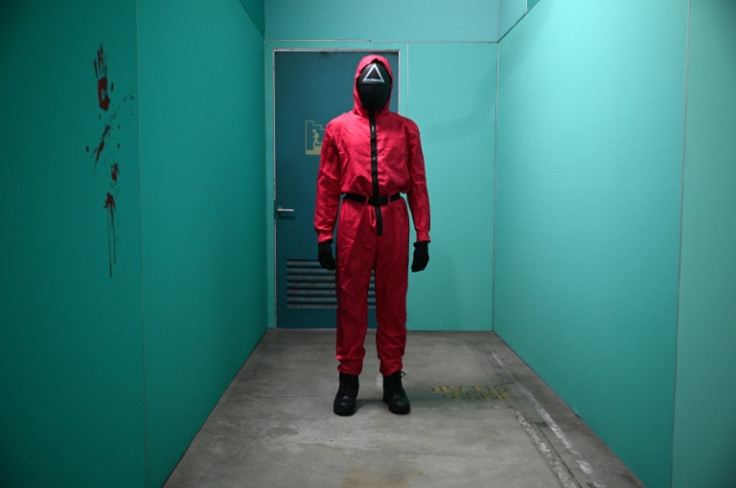 The 'Squid Game' guards in the fuchsia jumpsuits with the black masks bearing symbols are part of the attraction