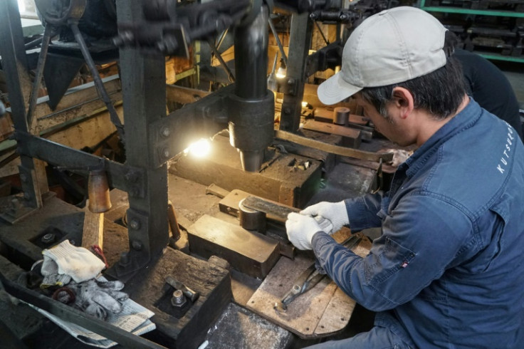 Yoshihiro Yauji places a 'santoku', a multipurpose knife, under a spring hammer, continuing a tradition dating back centuries