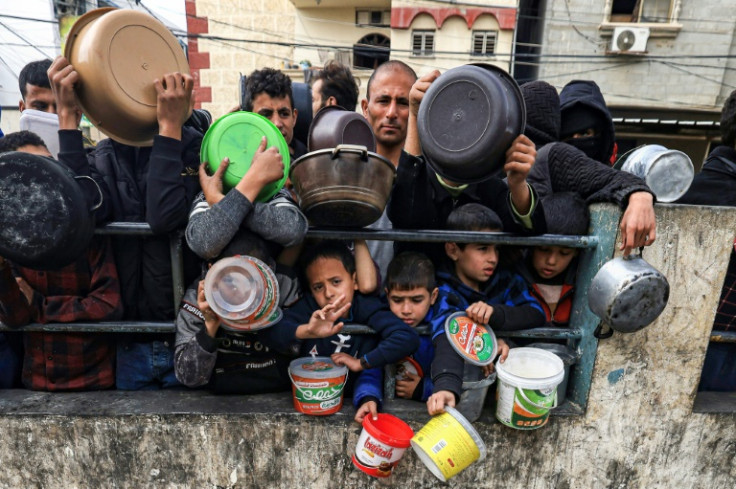 Palestinians wait to collect food at a donation point in a refugee camp in Rafah