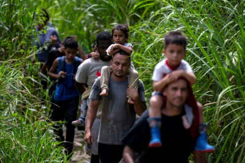 Migrants carrying children walk by the jungle near Bajo Chiquito village, the first border control of the Darien Province in Panama, on September 22, 2023