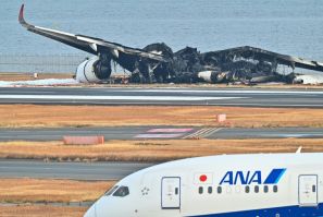 The burned-out wreckage of a Japan Airlines passenger plane sits on the tarmac at Tokyo International Airport