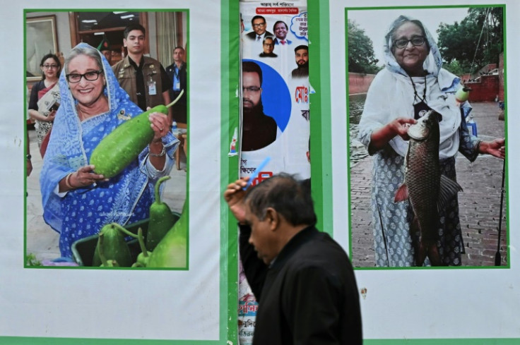 A man passes posters of Prime Minister Sheikh Hasina: she was praised for opening Bangladesh's doors to hundreds of thousands of Rohingya refugees fleeing a 2017 military crackdown in neighbouring Myanmar