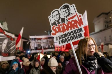 A woman holds a banner reading 'Solidarity with Kaminski and Wasik' to protest their arrest in front of the Presidential Palace