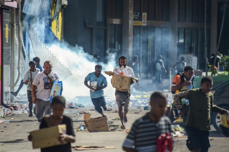 People run with merchandise as crowds leave shops with looted goods amid a state of unrest in Port Moresby