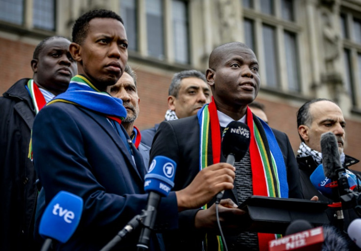 South Africa's Minister of Justice Ronald Lamola (R) talks to reporters  after the first day of hearings in a case Israel and its US ally have derided
