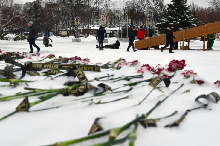 Children play on an ice slide in Stary Oskol, next to a makeshift memorial for victims of shelling attacks on Belgorod