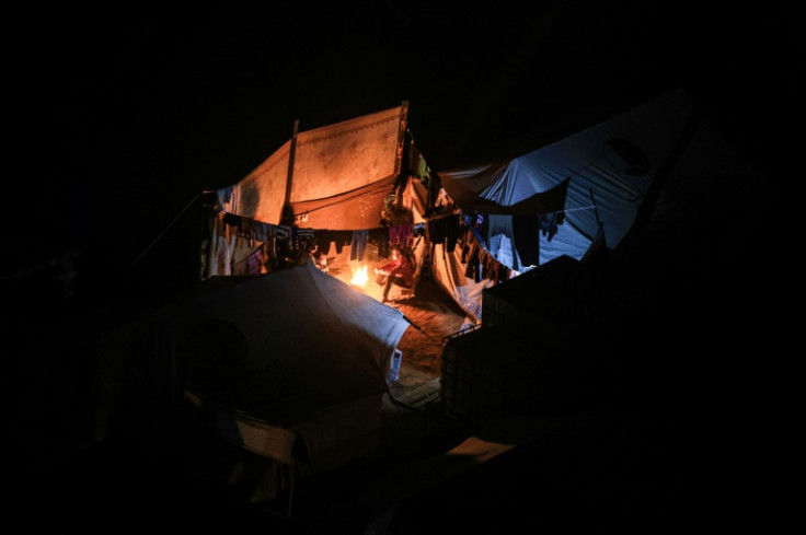 Displaced Palestinians sit around a fire next to a tent at a makeshift camp in Rafah on Tuesday