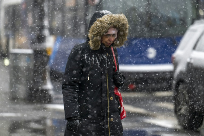 A woman walks as snow falls during a storm in New York City on January 19, 2024, but several parts of the country were getting pummelled by blizzard conditions