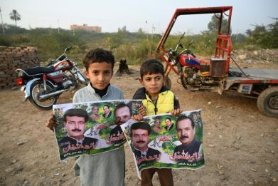 Children pose with election posters of Pakistan Muslim League Nawaz (PML-N) party candidates in Mianwali, the native town of jailed former Prime Minister Imran Khan