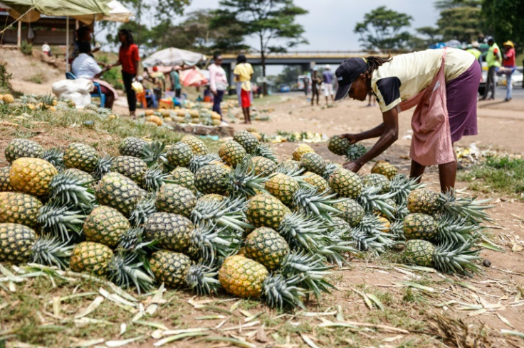 A vendor displays pineapples while waiting for customers at an informal market