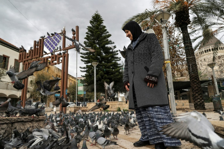 A woman stands among pigeons at the square outside the Roman Catholic Basilica of the Annunciation in Nazareth in northern Israel