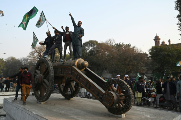 TLP supporters wave flags from on top of a cannon  in Lahore
