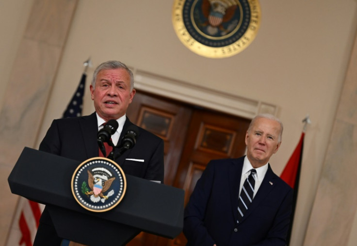King Abdullah II of Jordan speaks to the press as US President Joe Biden looks on in the Cross Hall of the White House