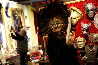 A visitor poses with a carnival mask in the salon of the Venice Art Mask workshop in Shkoder, Albania