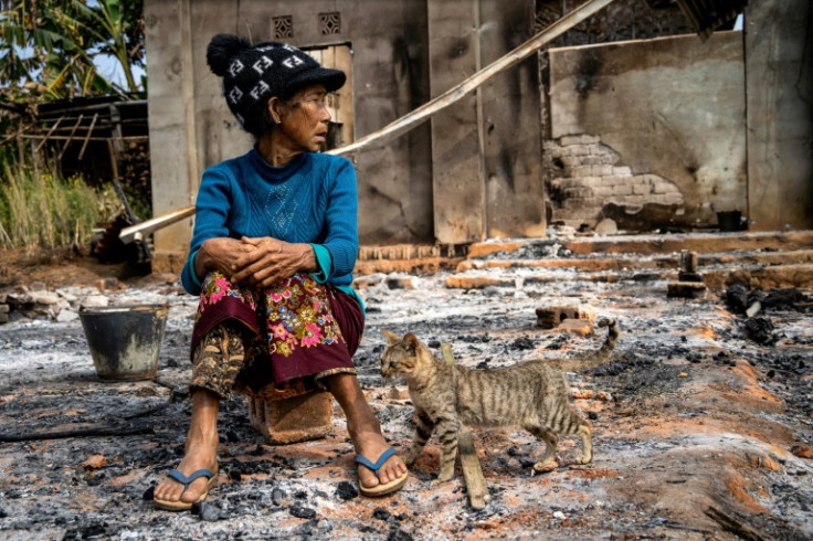 A woman sits in front of her house, damaged in fighting between Myanmar's military and the Kachin Independence Army