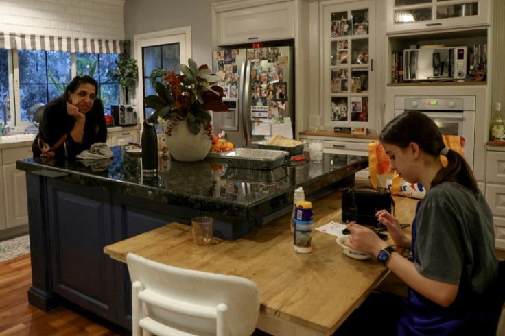 Sigal Chayak, displaced from northern Israel, looks on as her daughter Shani tastes the food she prepared in a host kitchen in Tel Aviv