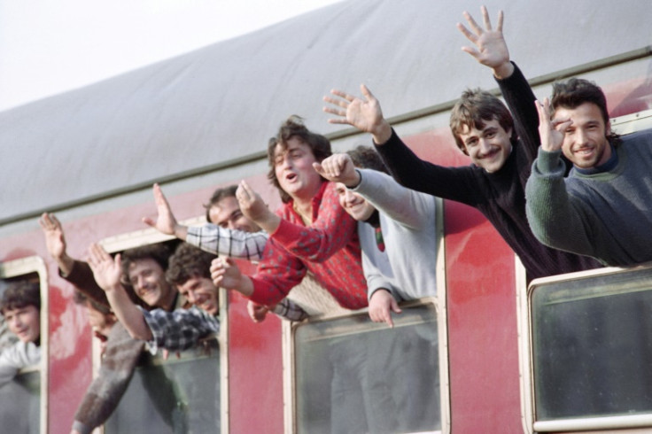 Albanian refugees wave as they leave the Italian port of Brindisi by train in March 1991