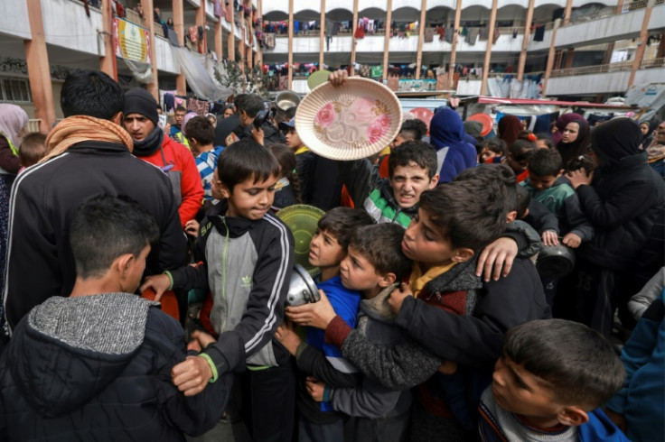 Displaced Palestinian children gather to receive food at a government school in Rafah in the southern Gaza Strip