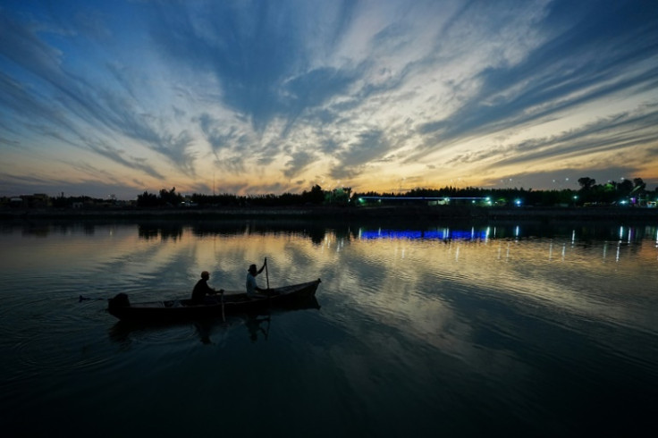 Iraqi fishermen row their boat on the Euphrates River at Nasiriyah