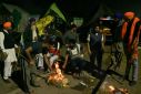 Indian farmers warm up around a bonfire during a protest demanding minimum crop prices
