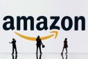 This illustration photograph taken on October 30, 2023, in Mulhouse, eastern France, shows figurines next to a screen displaying a logo of Amazon, a US multinational technology e-commerce company.