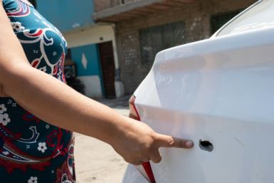 A businesswoman shows a bullet hole in her vehicle fired by gang members intimidating her to pay for protection in Lima