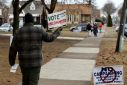 A volunteer asks voters to cast an uncommitted ballot, instead of voting for US President Joe Biden, in Dearborn, Michigan