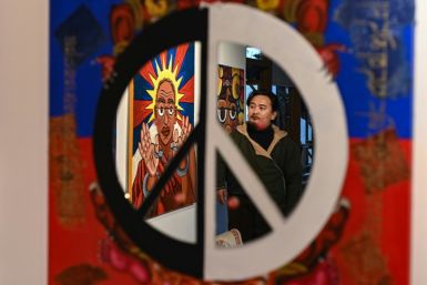 Tashi Nyima, an exiled Tibetan artist, is seen reflected in a mirror while looking at his paintings in Dharamsala